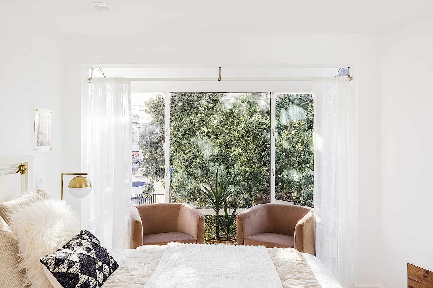 Grande fenêtre derrière deux fauteuils en cuir dans une chambre à coucher bien éclairée