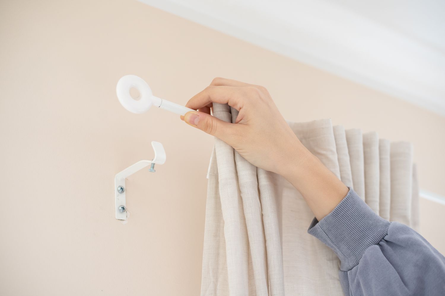 Extremo de la barra de la cortina colocado en el gancho de pared