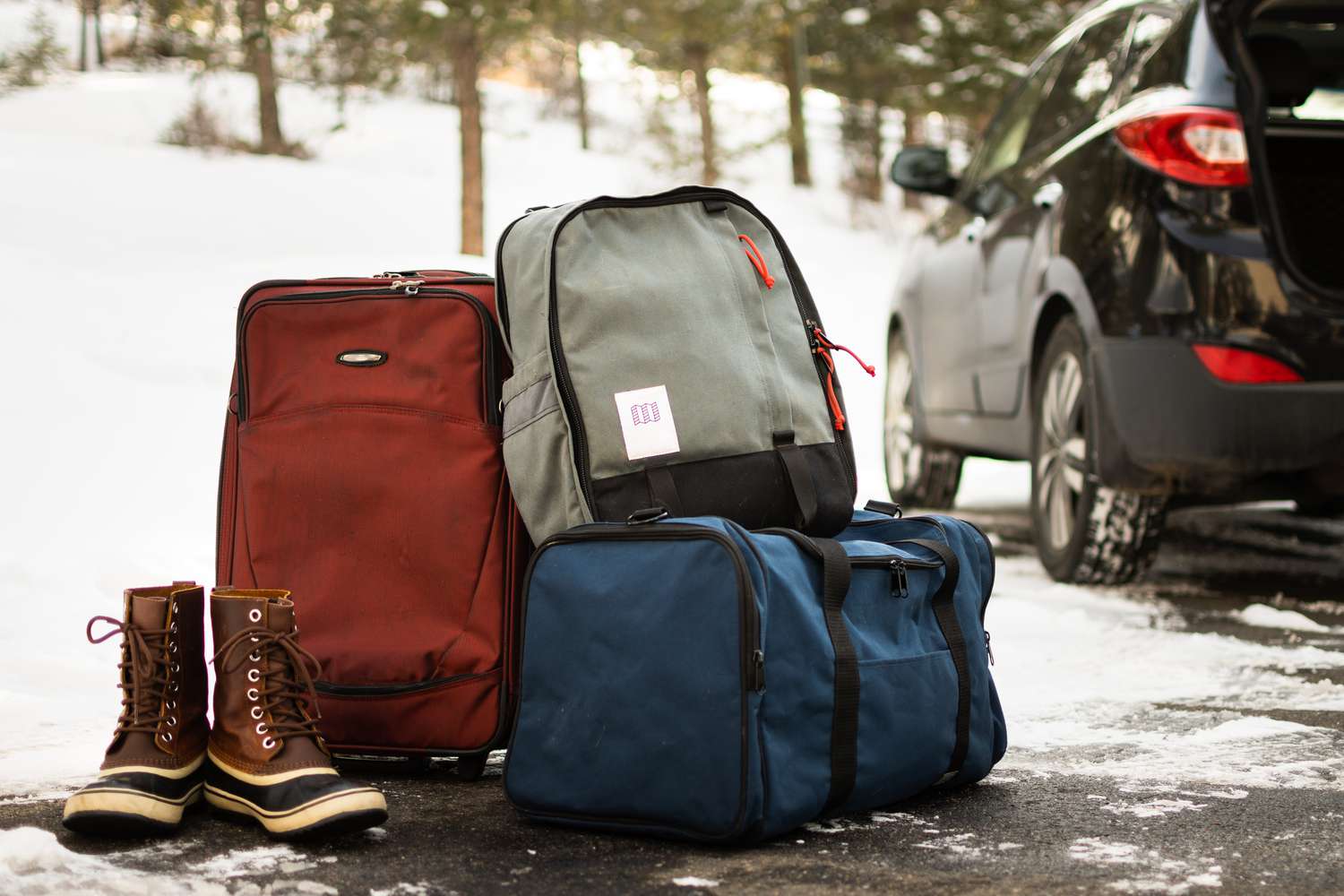 Rucksäcke und Seesäcke gepackt neben Schneeschuhen und Auto 