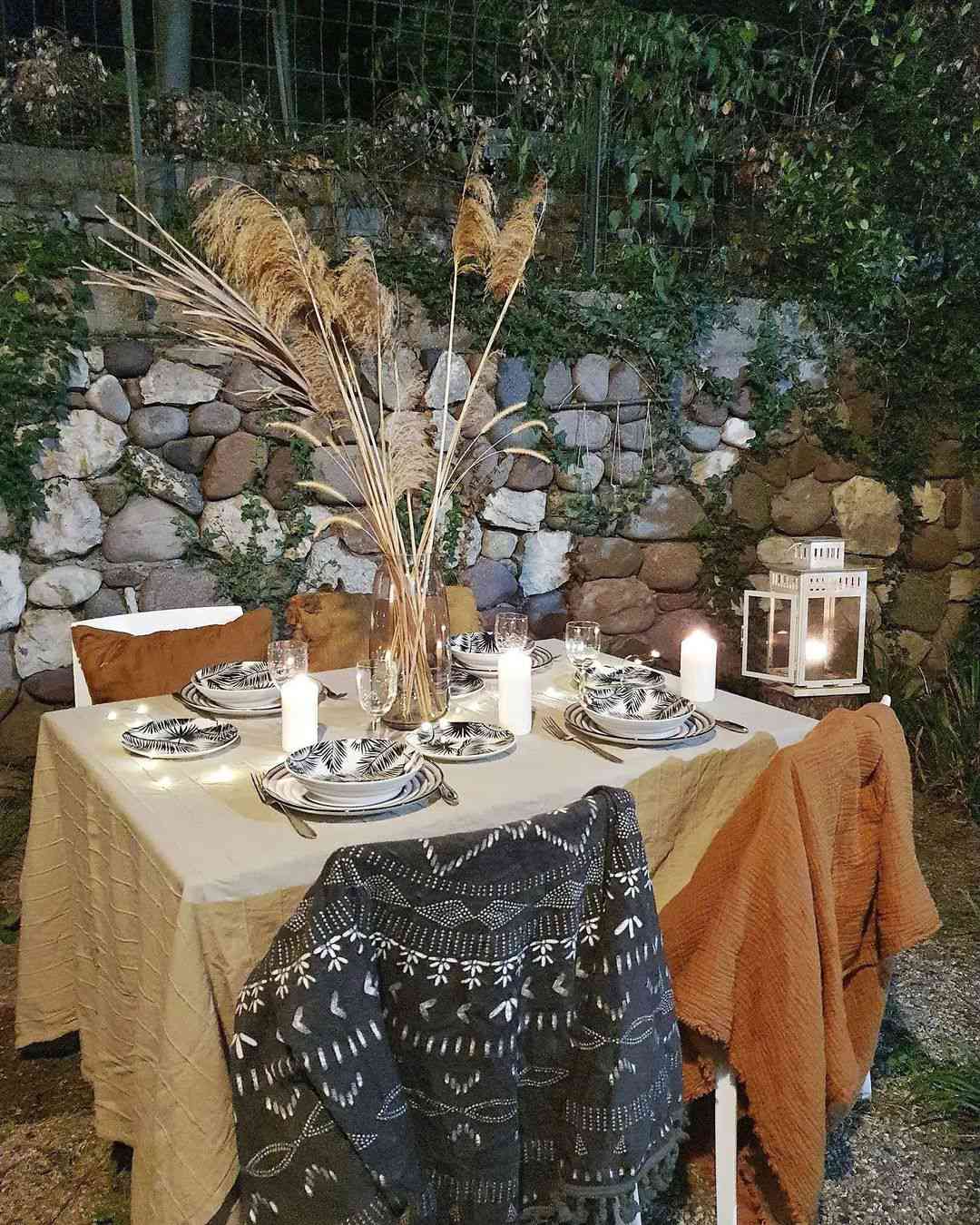 Mesa ao ar livre com velas, toalha de mesa de linho e grama alta dos pampas