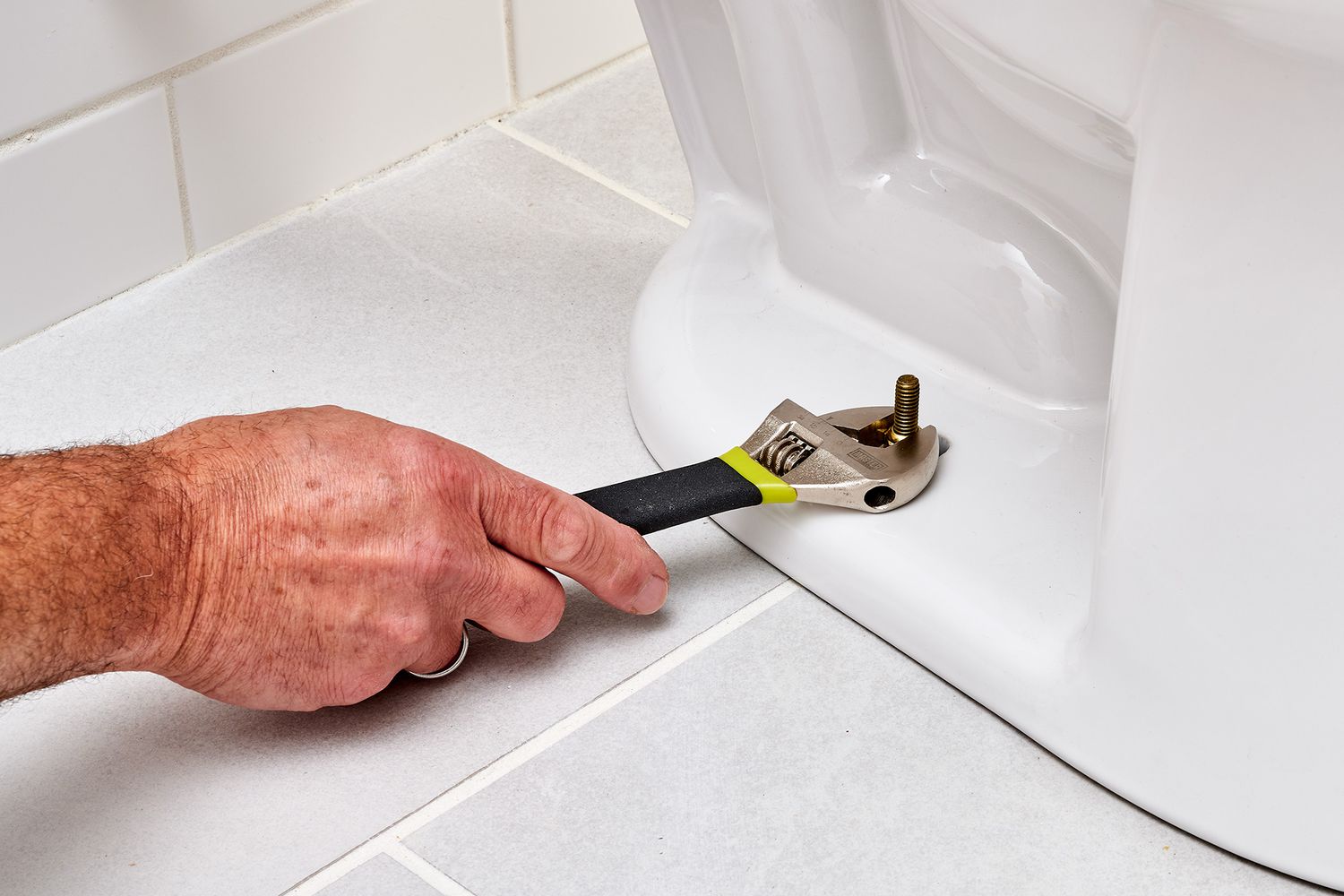Schrankschrauben am WC-Sockel mit Schraubenschlüssel angezogen