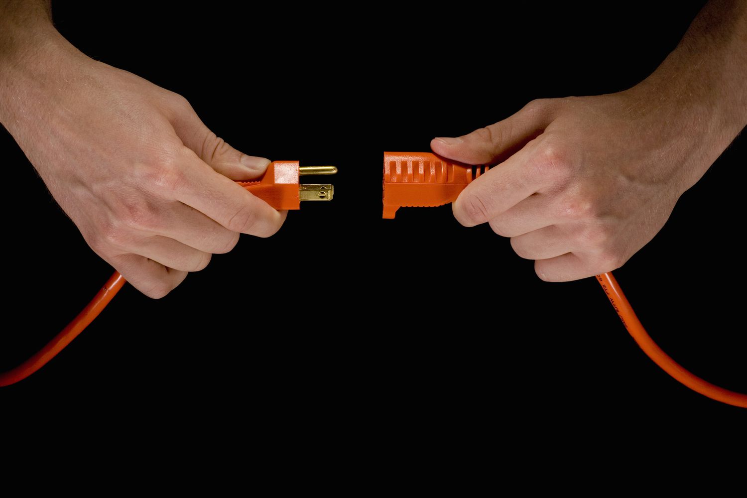 Homem segurando plugue elétrico laranja e cabo de extensão.