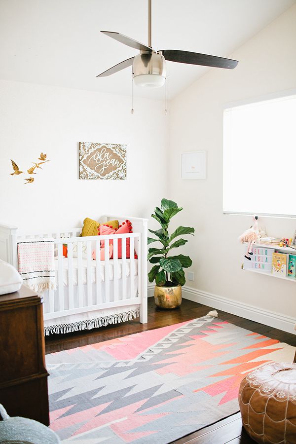 Simple, boho nursery with minimal decor and colorful rug