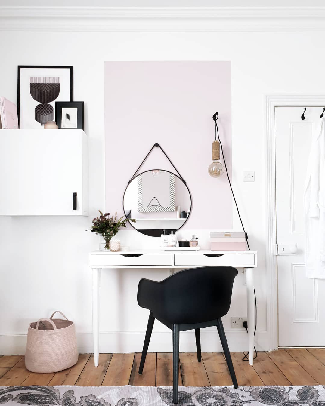 Weißes Zimmer mit schwarzem Stuhl und rosa Bodenkorb
