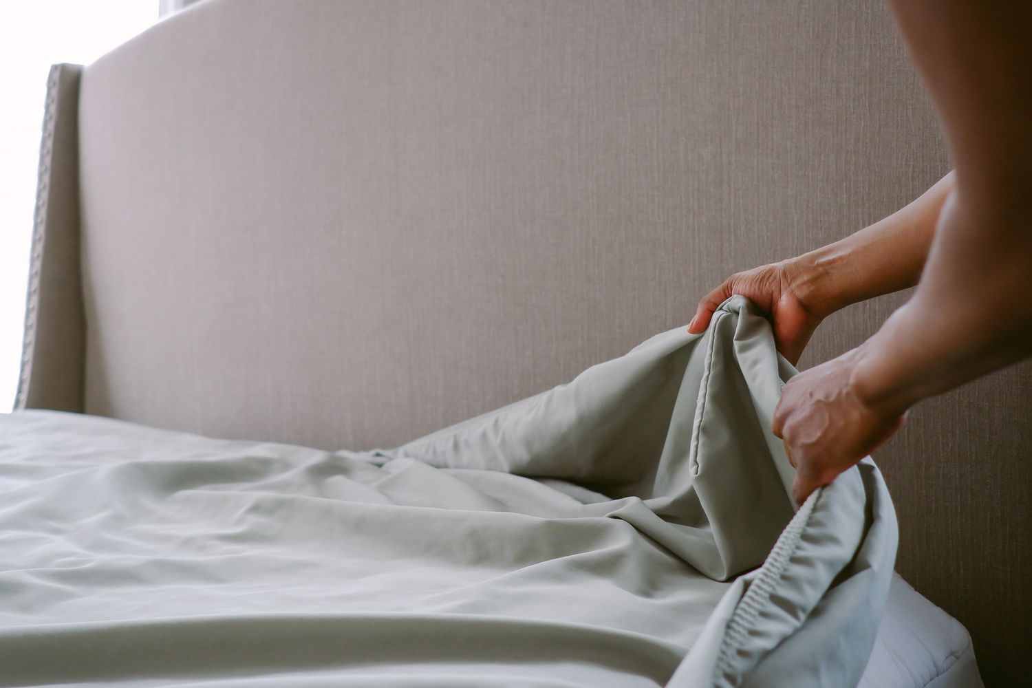 Person putting fitted sheet on a bed