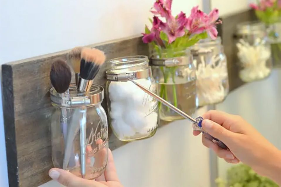 A woman installing a mason jar organizer in a bathroom
