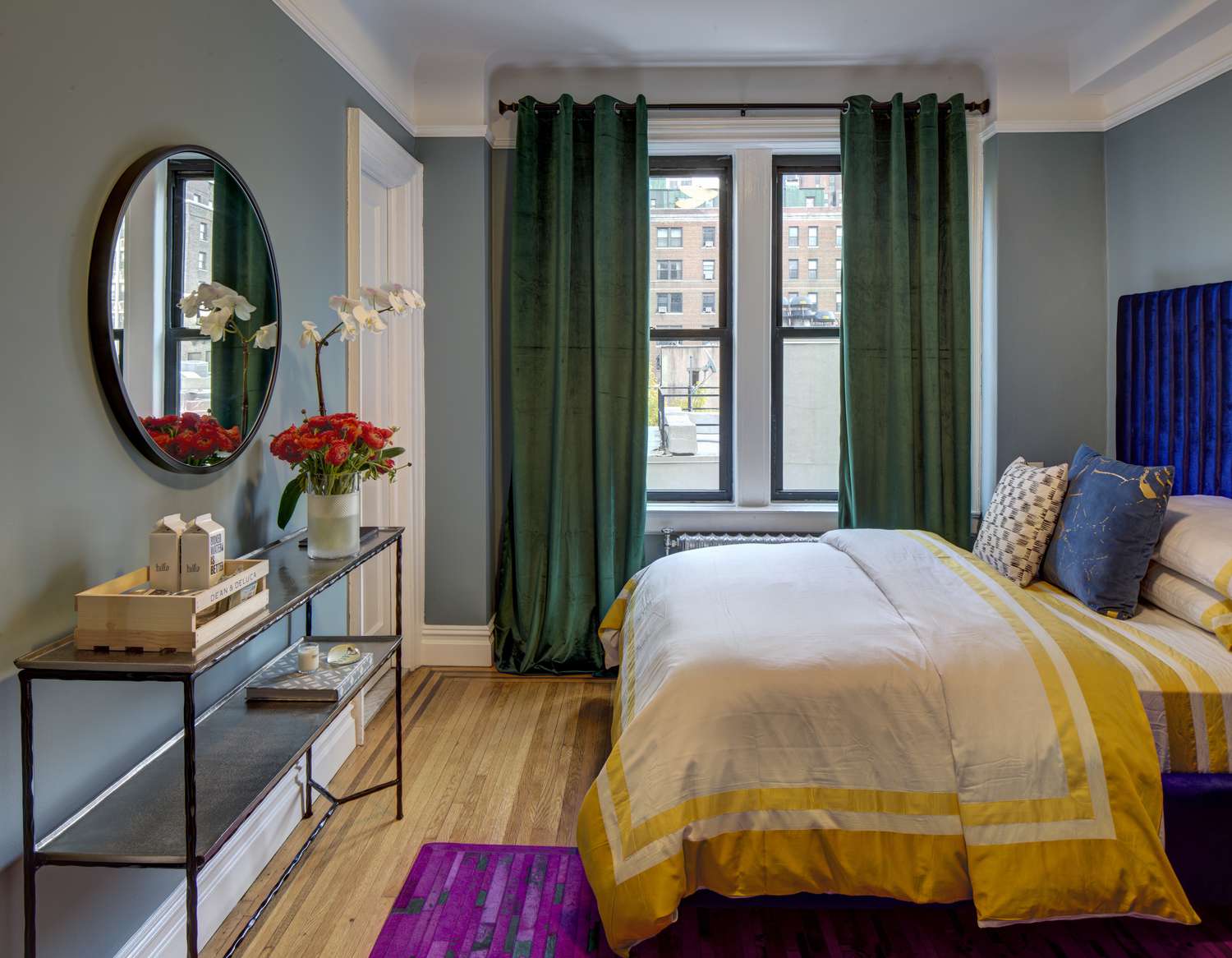 Farbenfrohes Schlafzimmer mit grünen Vorhängen, blaugrünen Wänden und weißer und gelber Bettdecke.