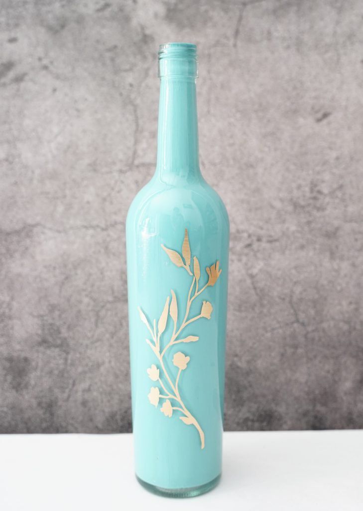 Botella pintada de azul con calcomanía floral dorada