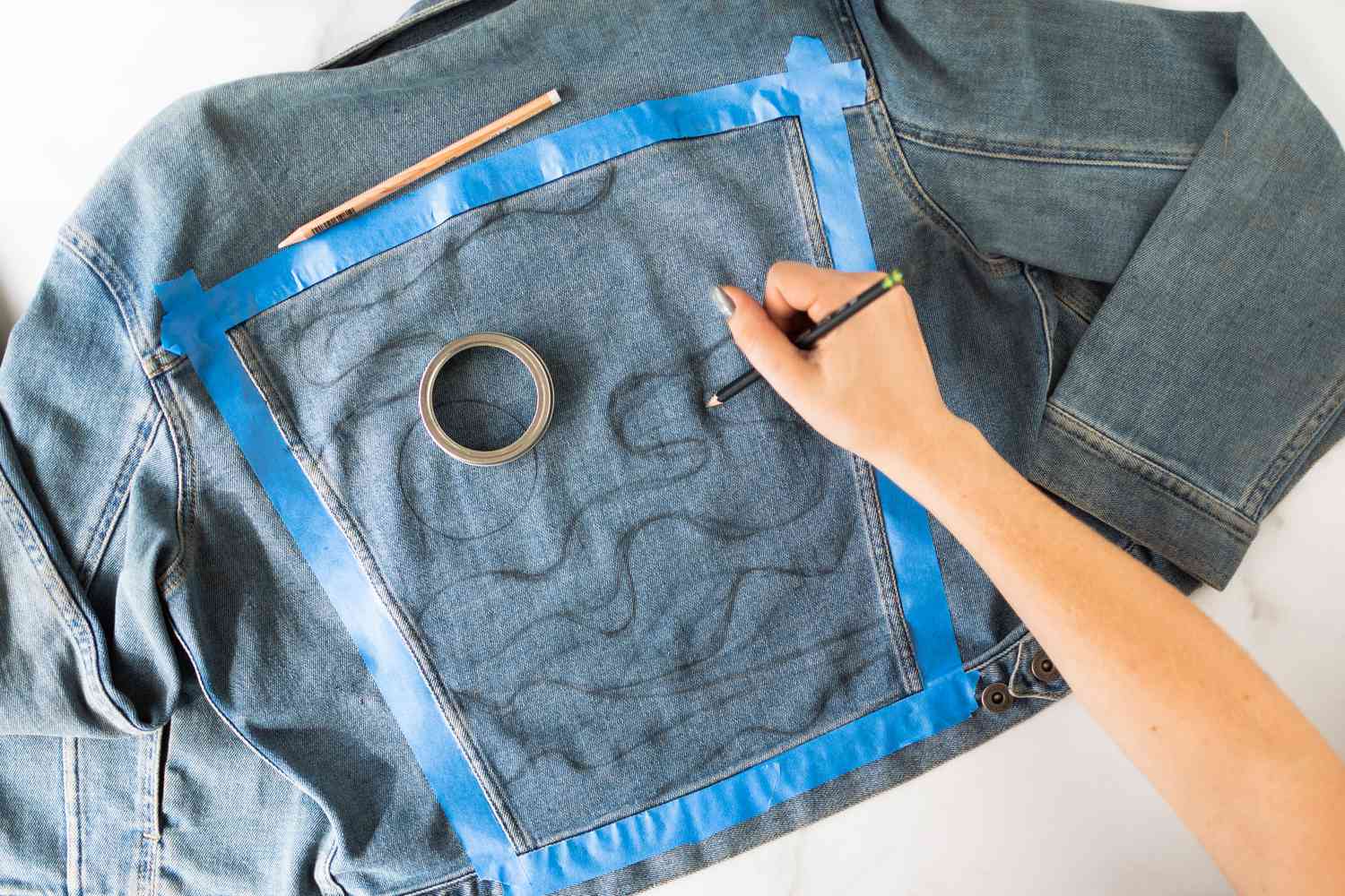 Desenho a lápis em tecido jeans dentro da seção de fita azul de pintor