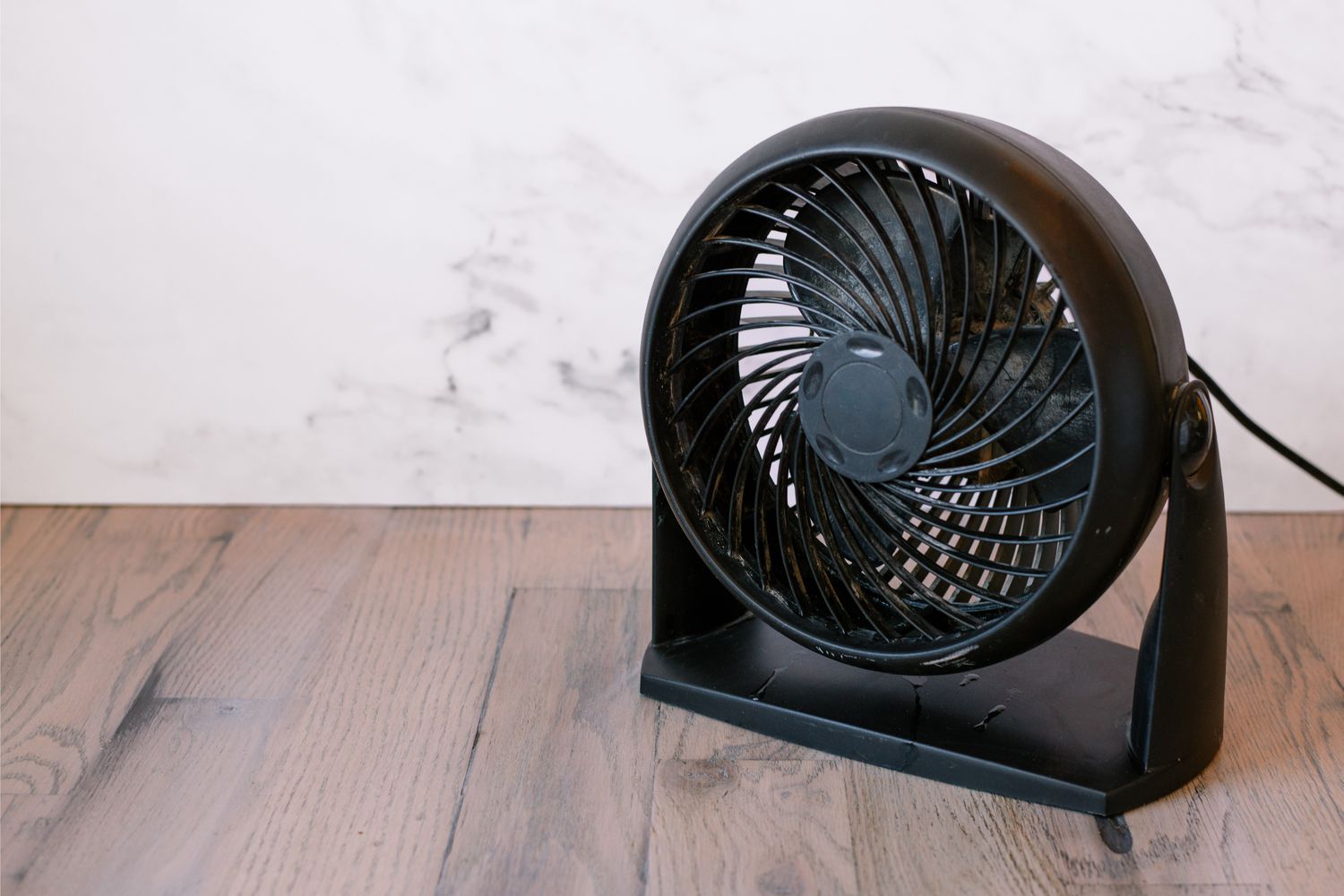 Suelo de madera secándose con un pequeño ventilador negro 