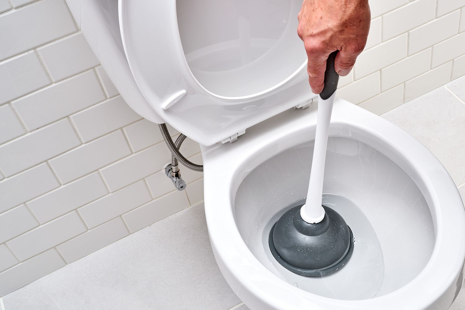 Plongeur blanc et noir à l'intérieur de la cuvette des toilettes vérifiant le niveau d'eau