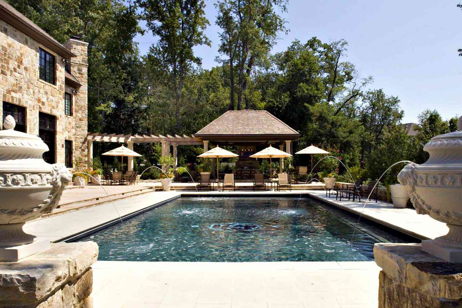 Mediterraner Pool mit wasserspeienden Löwenfontänen.