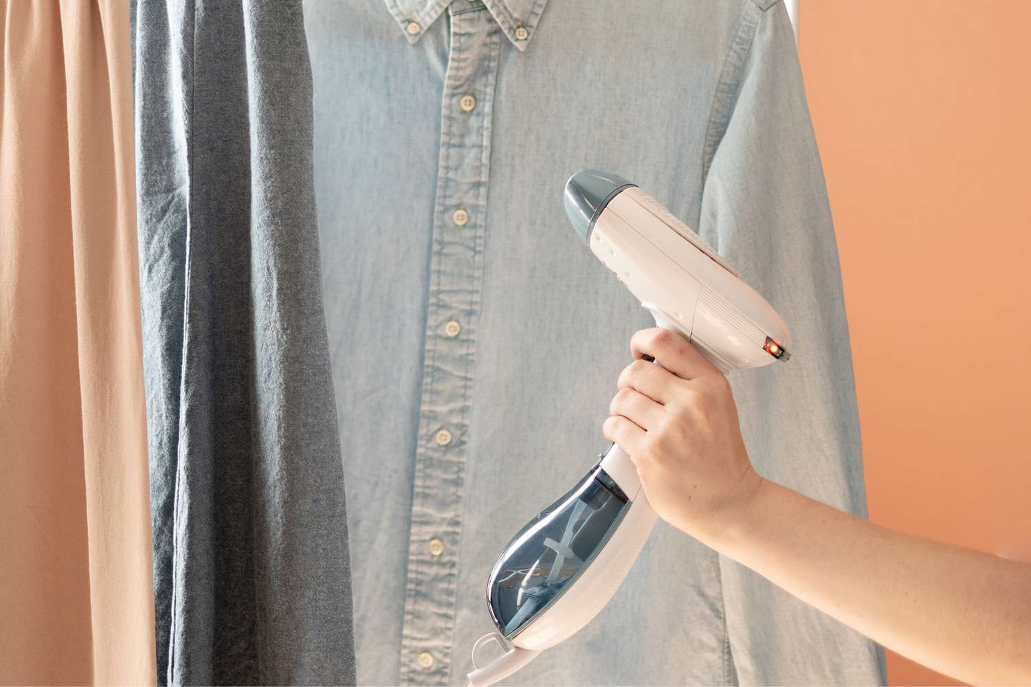 Kleidungsdampfer, der über ein Hemd mit Knopfleiste fährt, um Falten zu entfernen
