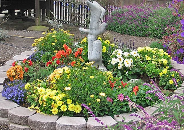 Jardín rocoso con plantas anuales de colores y escultura de gaviota