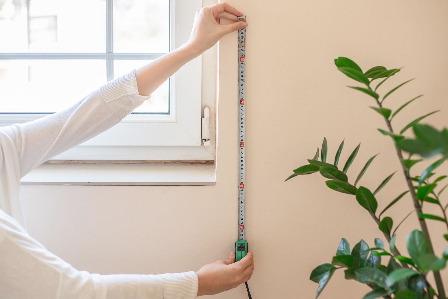 Curtain length being measured with measuring tape on side of window