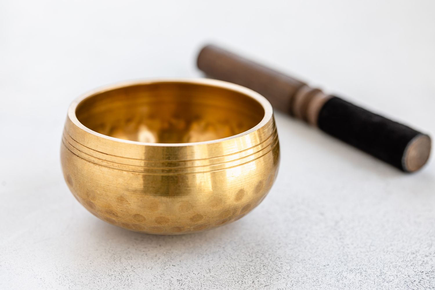 Gold metal bowl next to stick for sound vibration