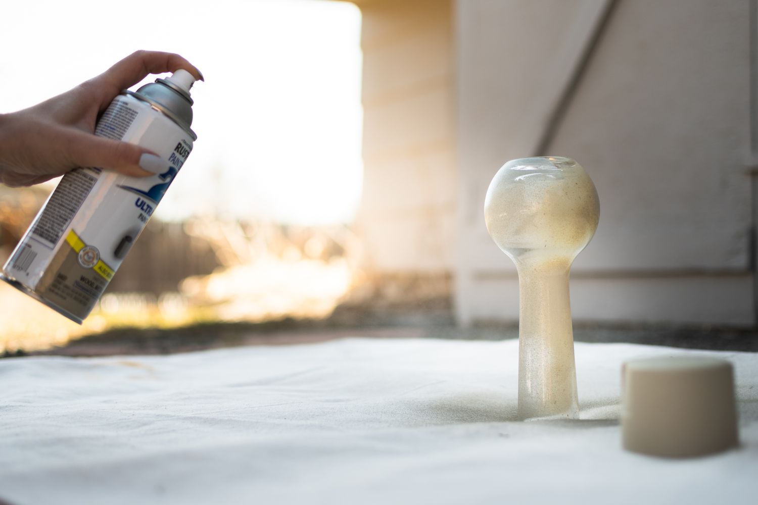 Vaso de vidro colocado de cabeça para baixo e pintado com spray dourado