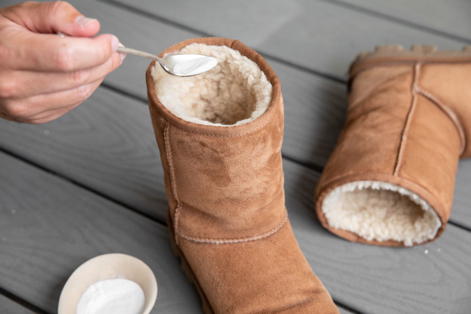 Someone spooning baking soda into an Ugg boot