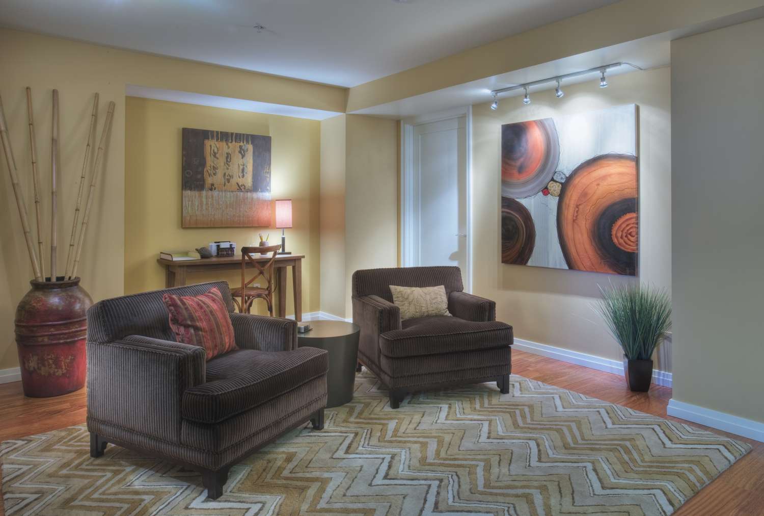 Salon avec meubles bruns, murs neutres, et deux peintures abstraites