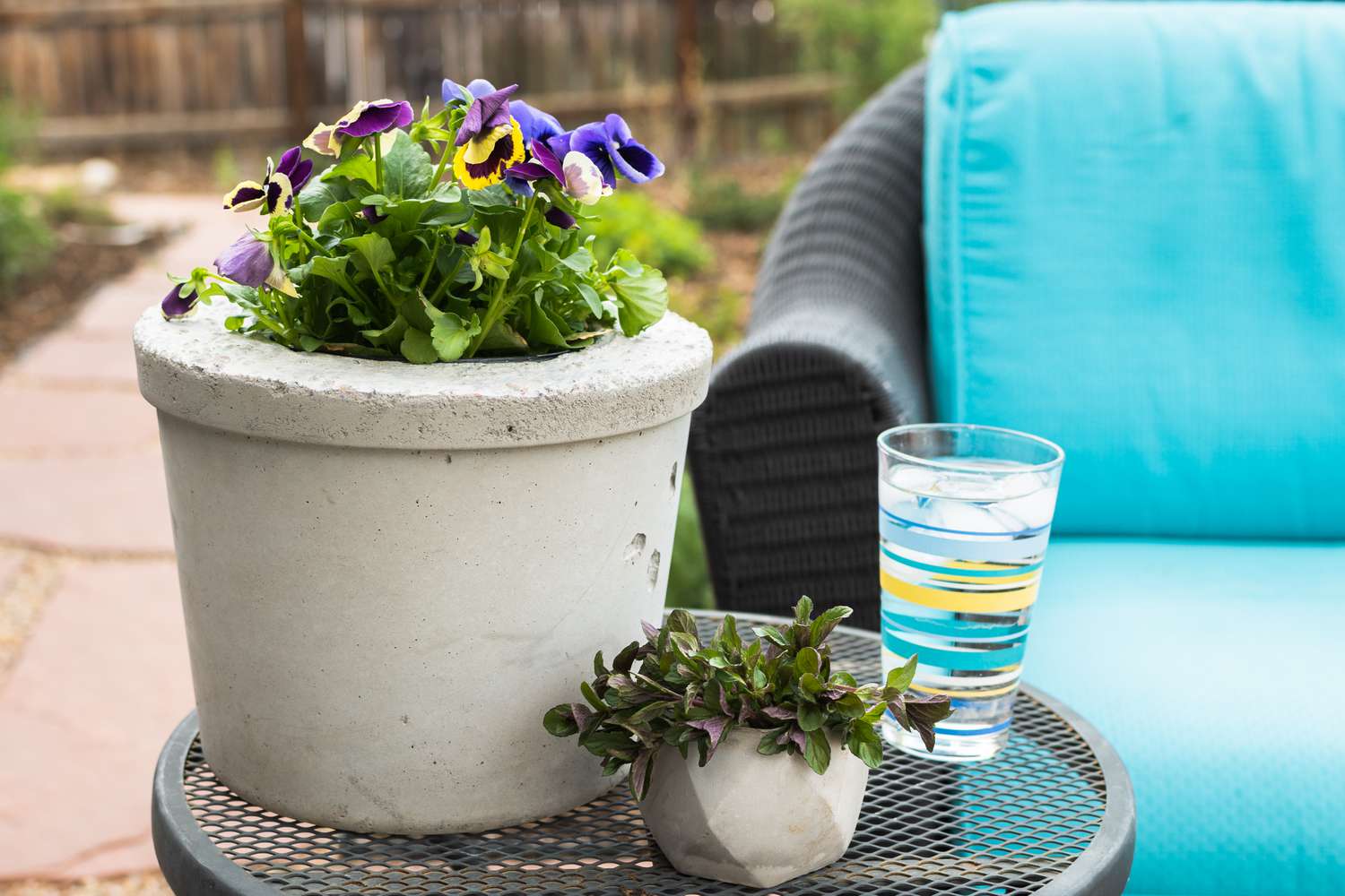 DIY große und kleine Pflanzgefäße auf Metalltisch im Freien neben einem Glas Wasser