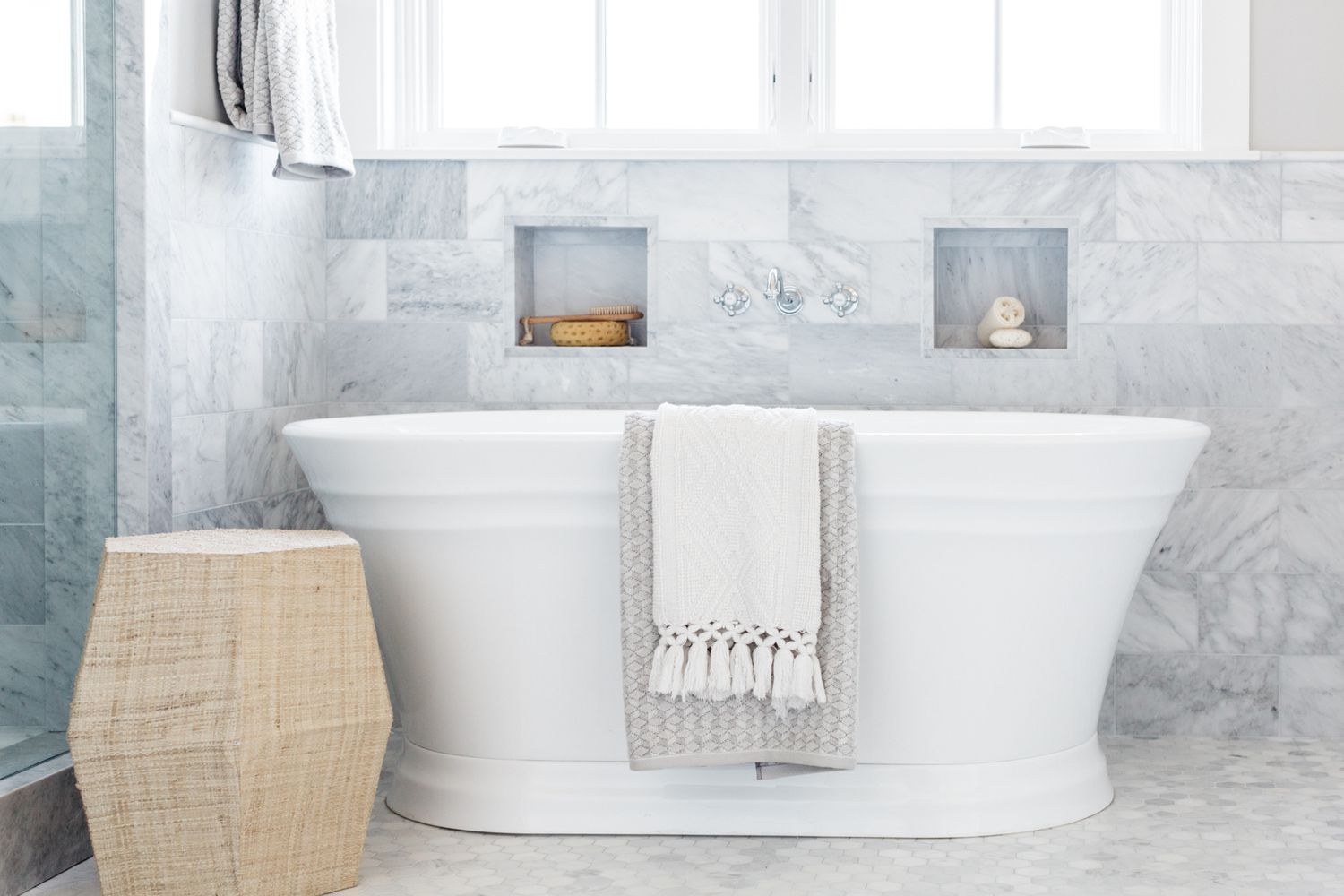 White bath tub with folded towels hanging over edge