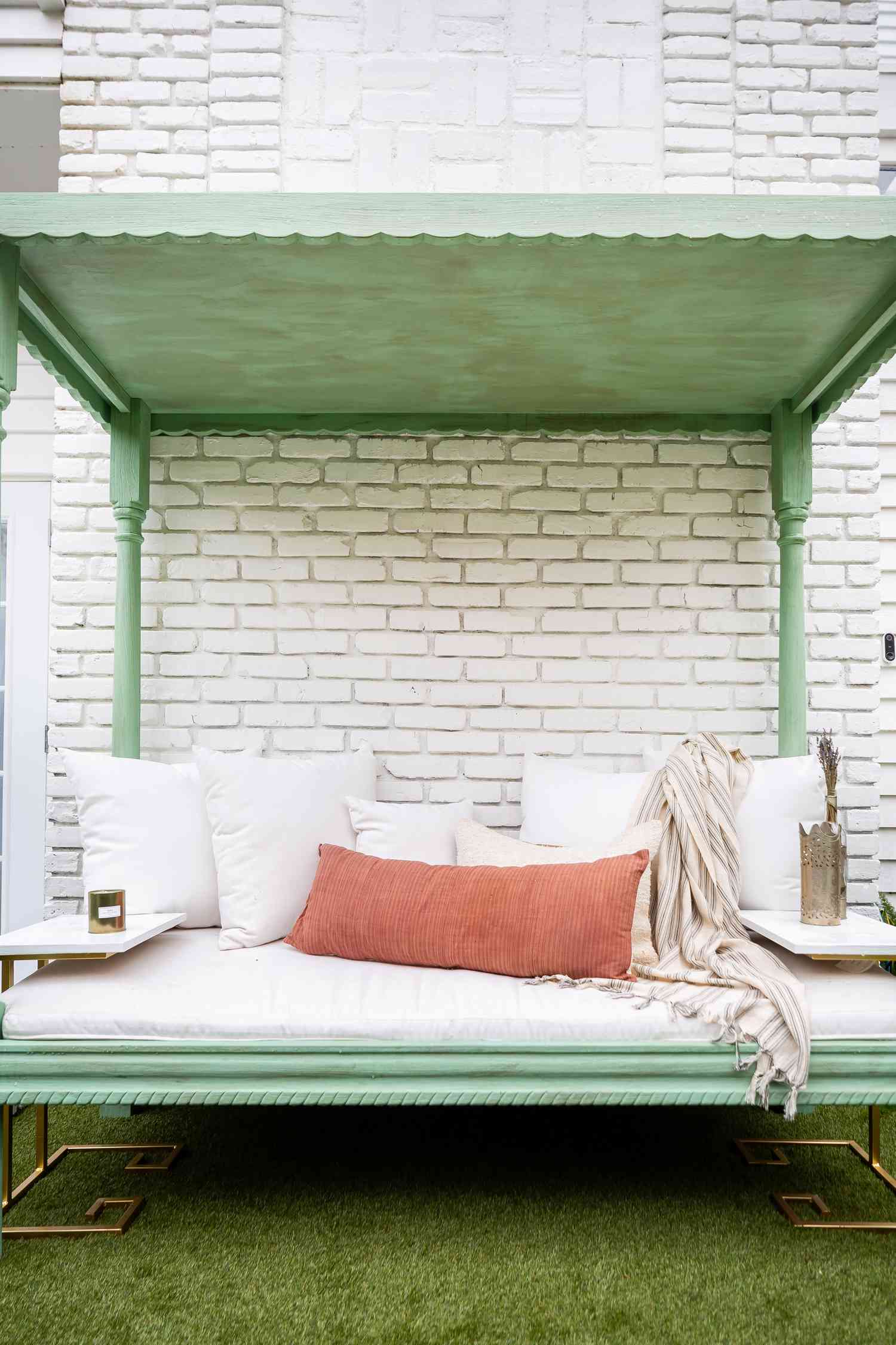Una cama de patio pintada en verde apagado. 