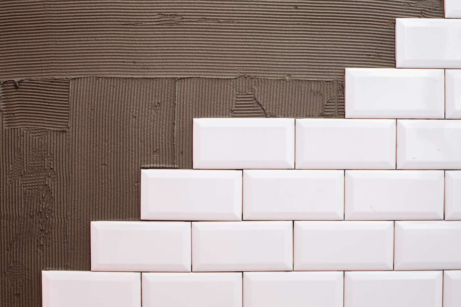 Carreaux de céramique blanche installés en rangées sur un mur adhésif