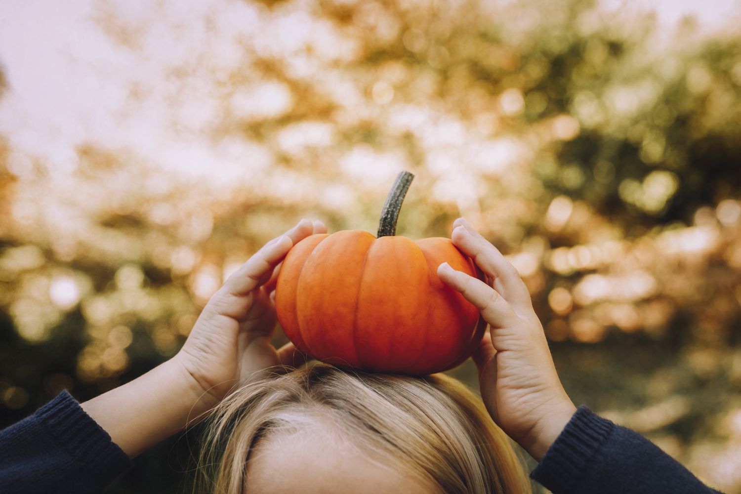 Imagen recortada de un niño balanceando una pequeña calabaza sobre su cabeza