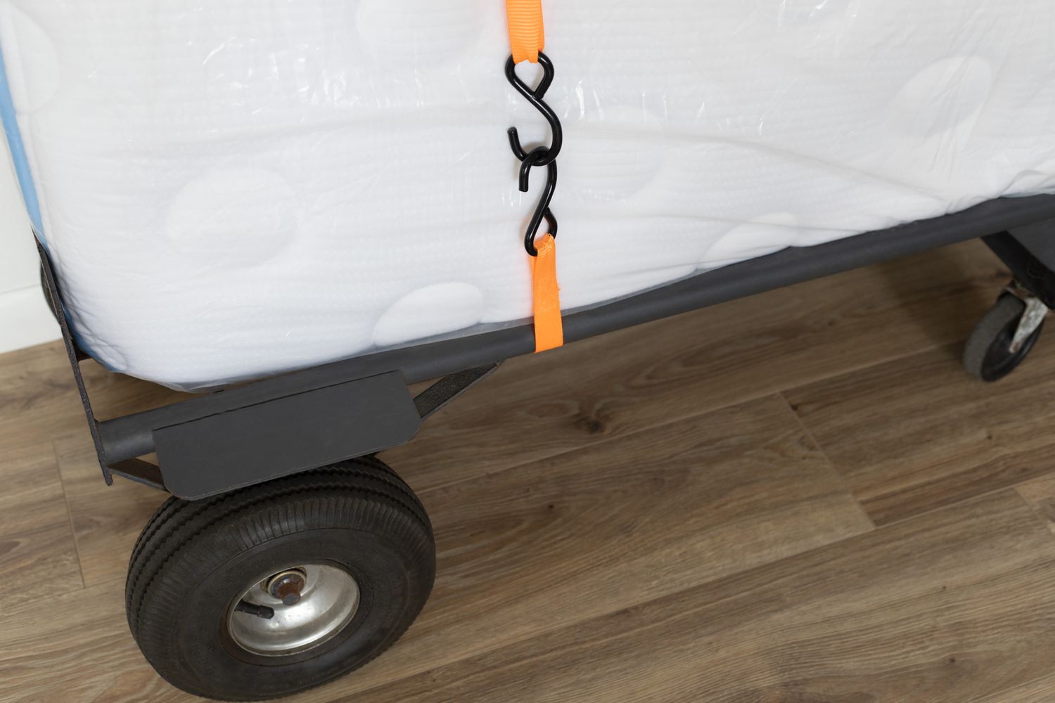 Matratze auf dem Möbelwagen platziert und mit orangefarbenen Spanngurten für den Umzug gesichert