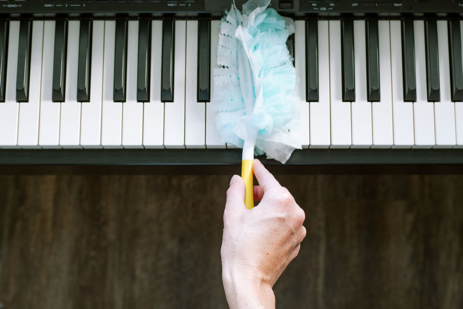Persona quitando el polvo de las teclas de plástico de un piano