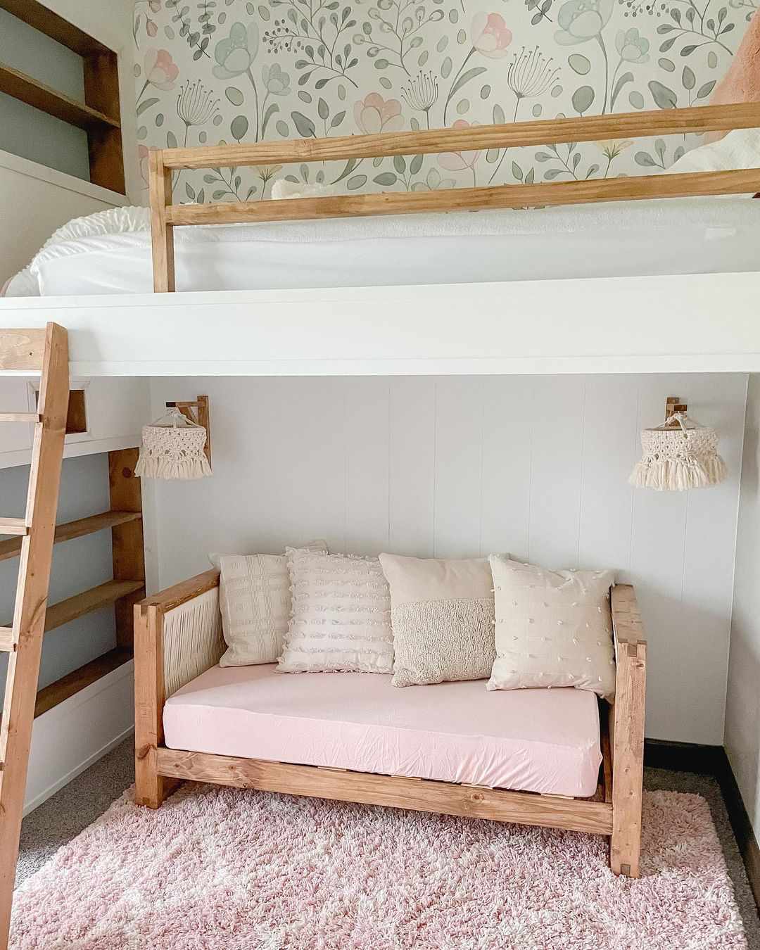 Una cama tipo loft en la habitación de un niño con un pequeño sofá y apliques en el nivel inferior.