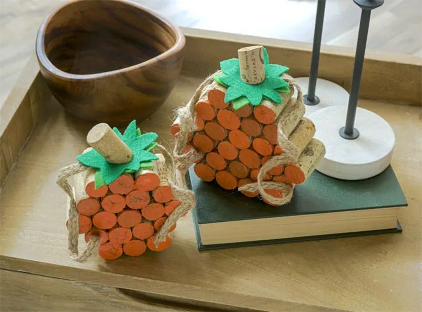 Dos calabazas hechas con corchos de vino, pintadas de naranja