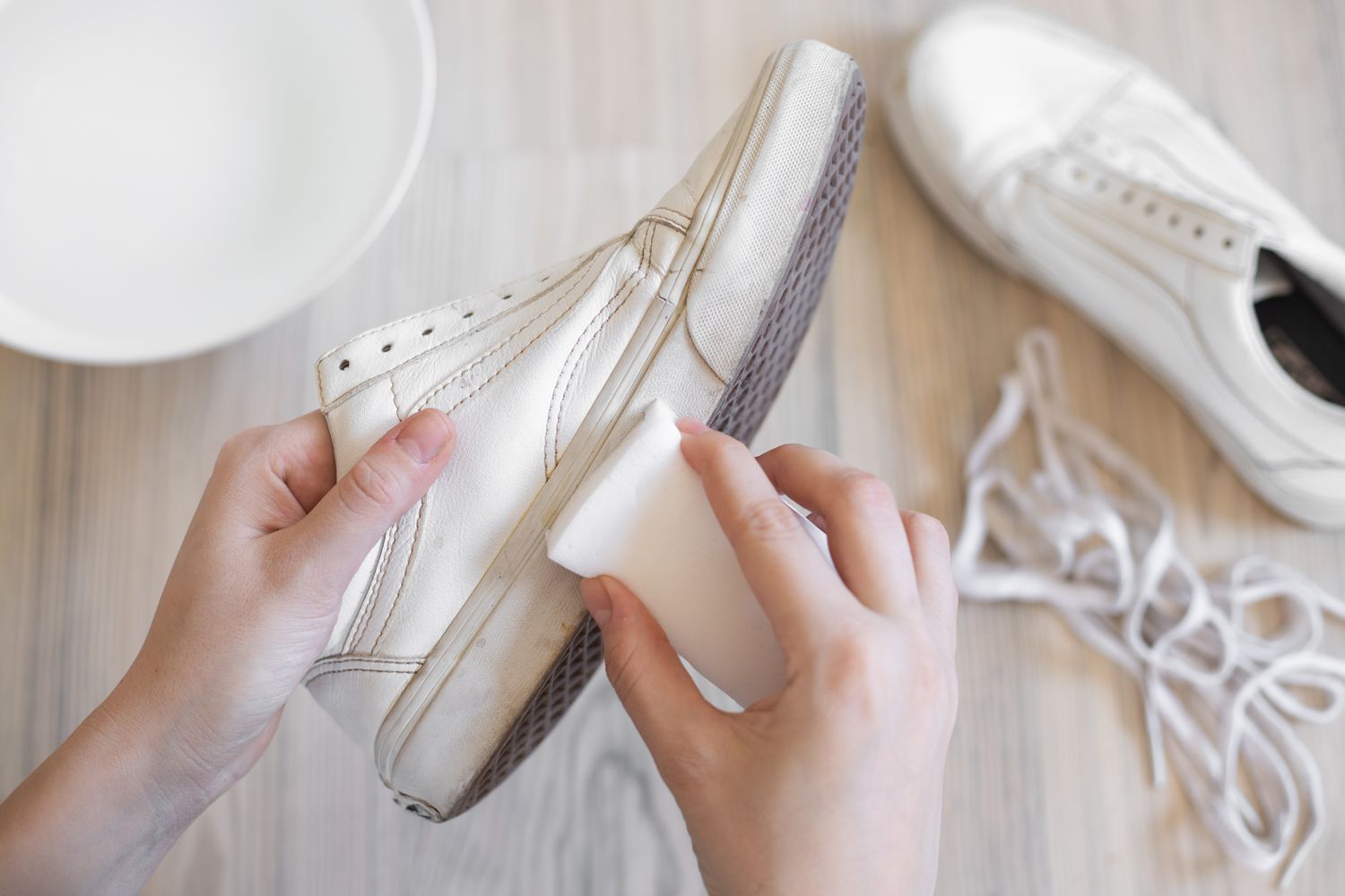 White Vans soles being cleaned with melamine sponge