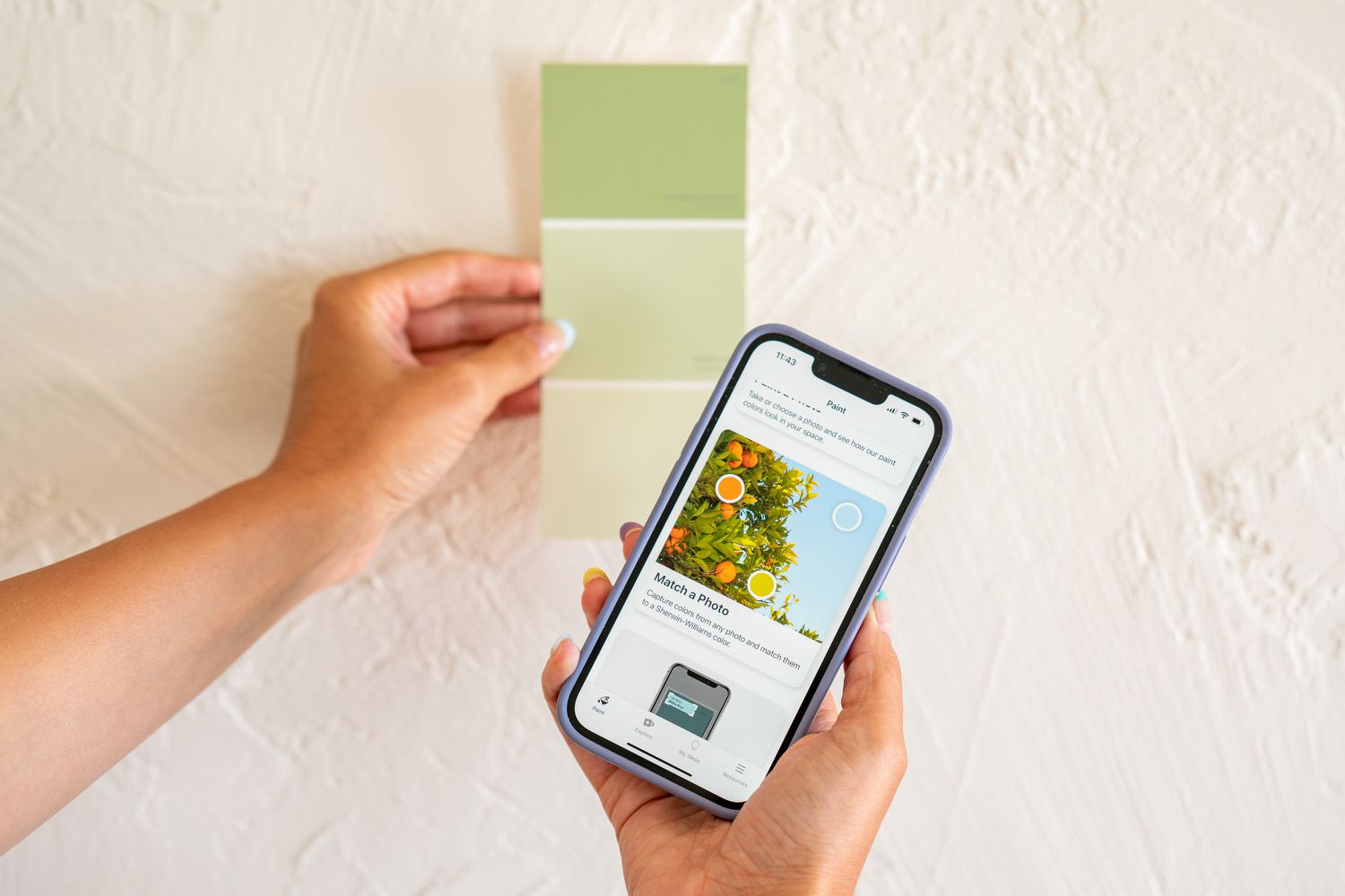 Grünes Farbmuster an der Wand neben der Farbvergleichs-App auf dem Smartphone