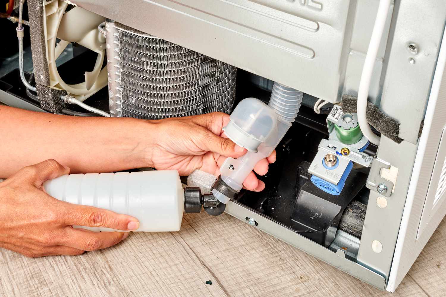 Botella de agua dirigiendo agua hacia el desagüe del frigorífico