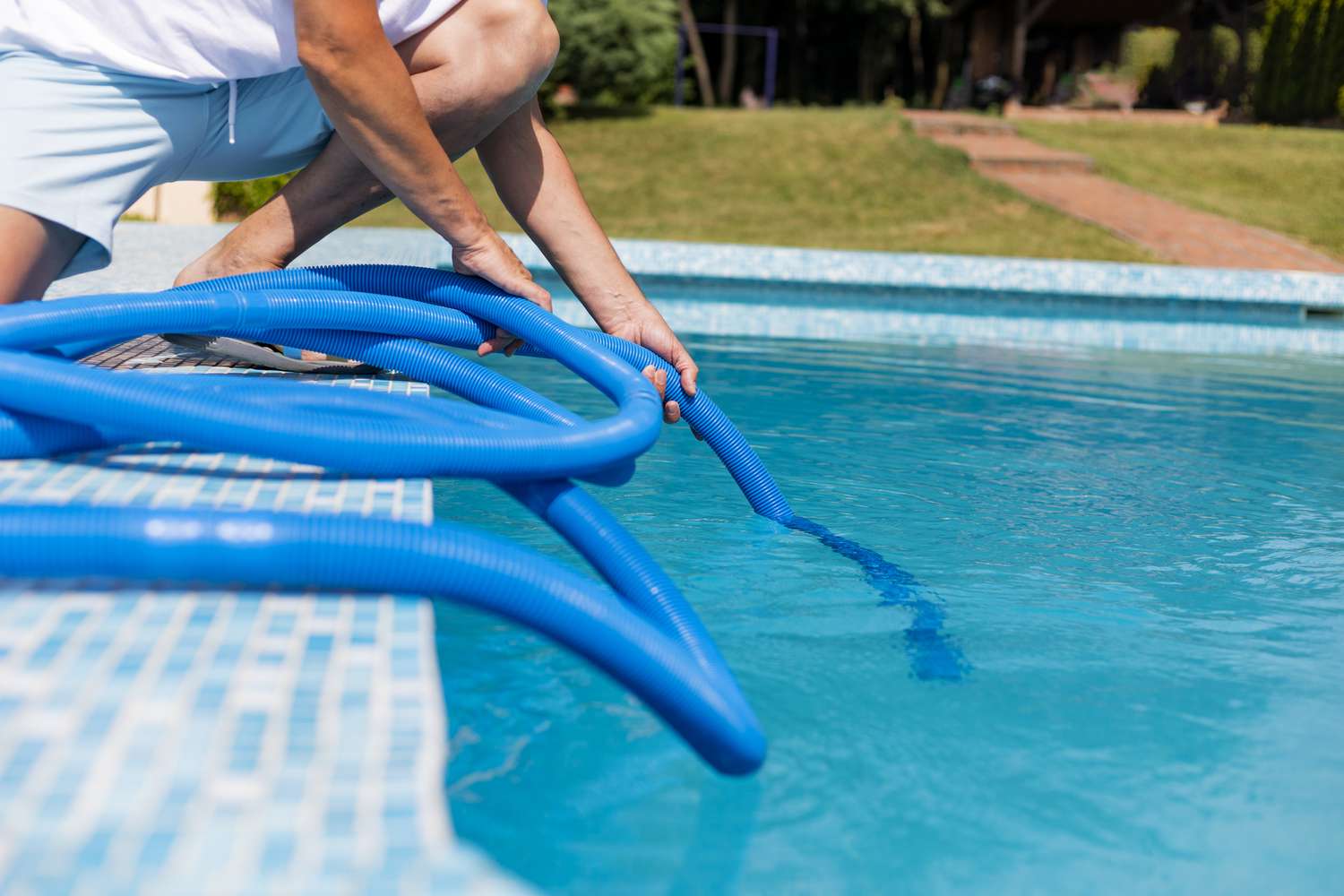 Hombre limpiando la piscina con una aspiradora de mano