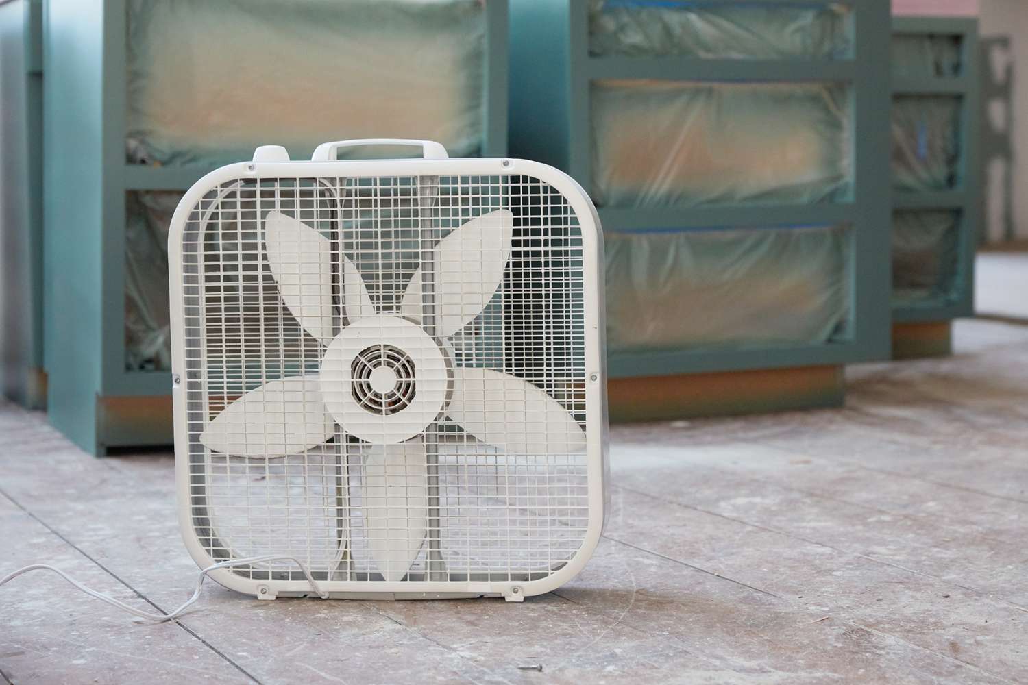 Ventilador cuadrado blanco soplando aire sobre los armarios de cocina imprimados