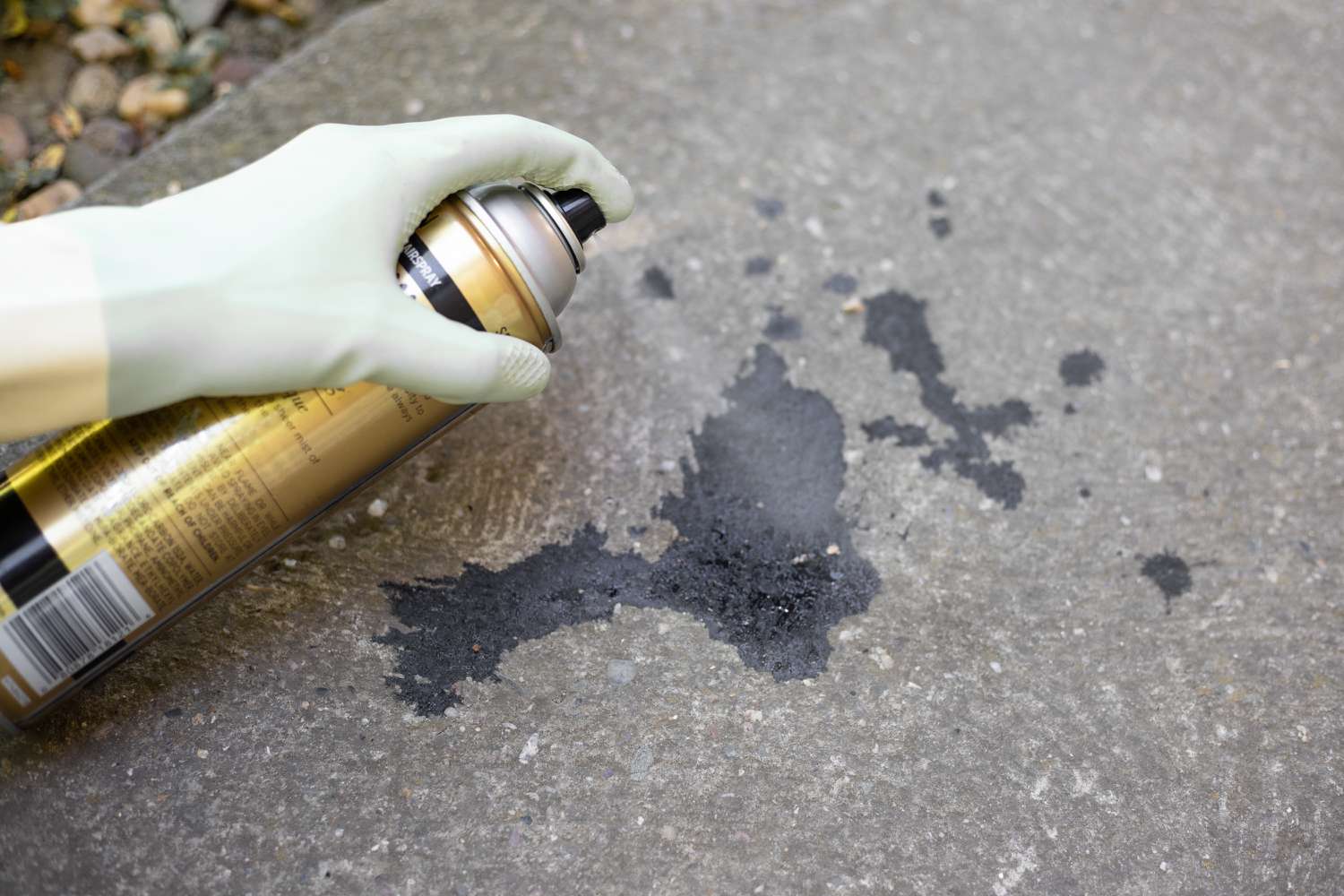 Schwarzer Ölfleck auf Beton mit Lösungsmittel besprüht 