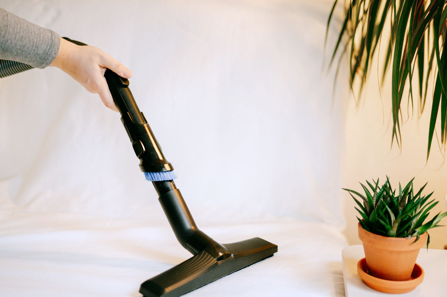Vacuum cleaning up matted fibers from white synthetic fabric cushion