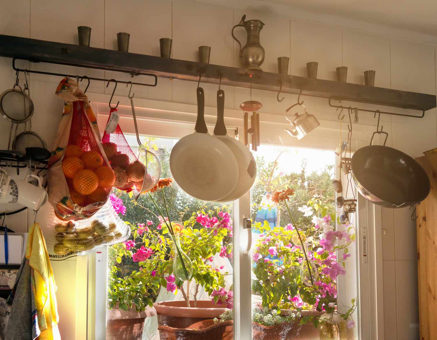 Innenfenster einer Sommerküche, dekoriert mit verschiedenen Küchenartikeln und Topfpflanzen auf der Fensterbank