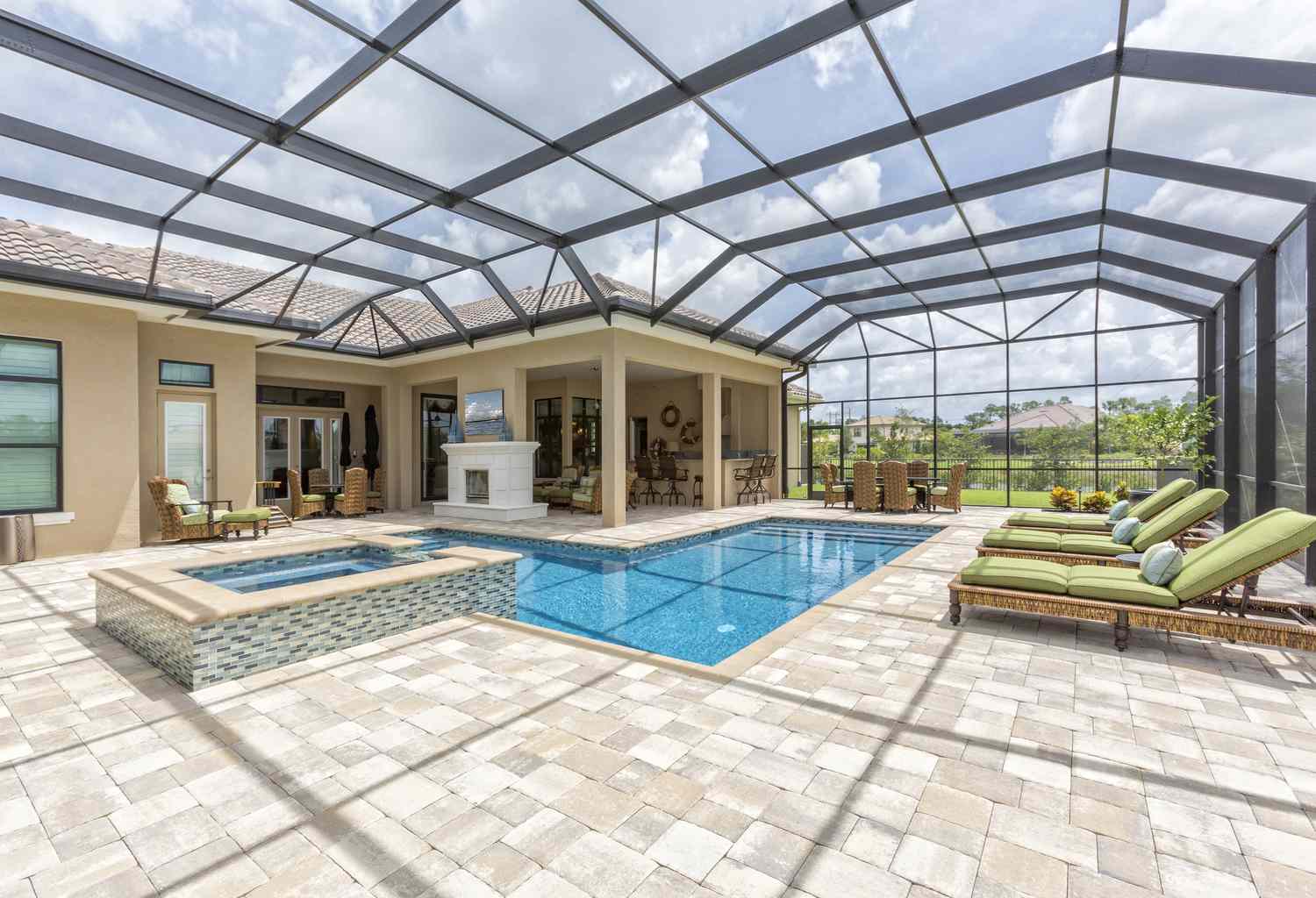 Uma piscina interna com teto de vidro e azulejos, bem como móveis verdes no pátio.