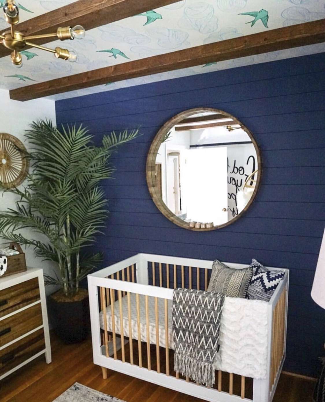 wallpaper mural used on the ceiling of a nursery, that also features painted shiplap, wood beams, and a large mirror