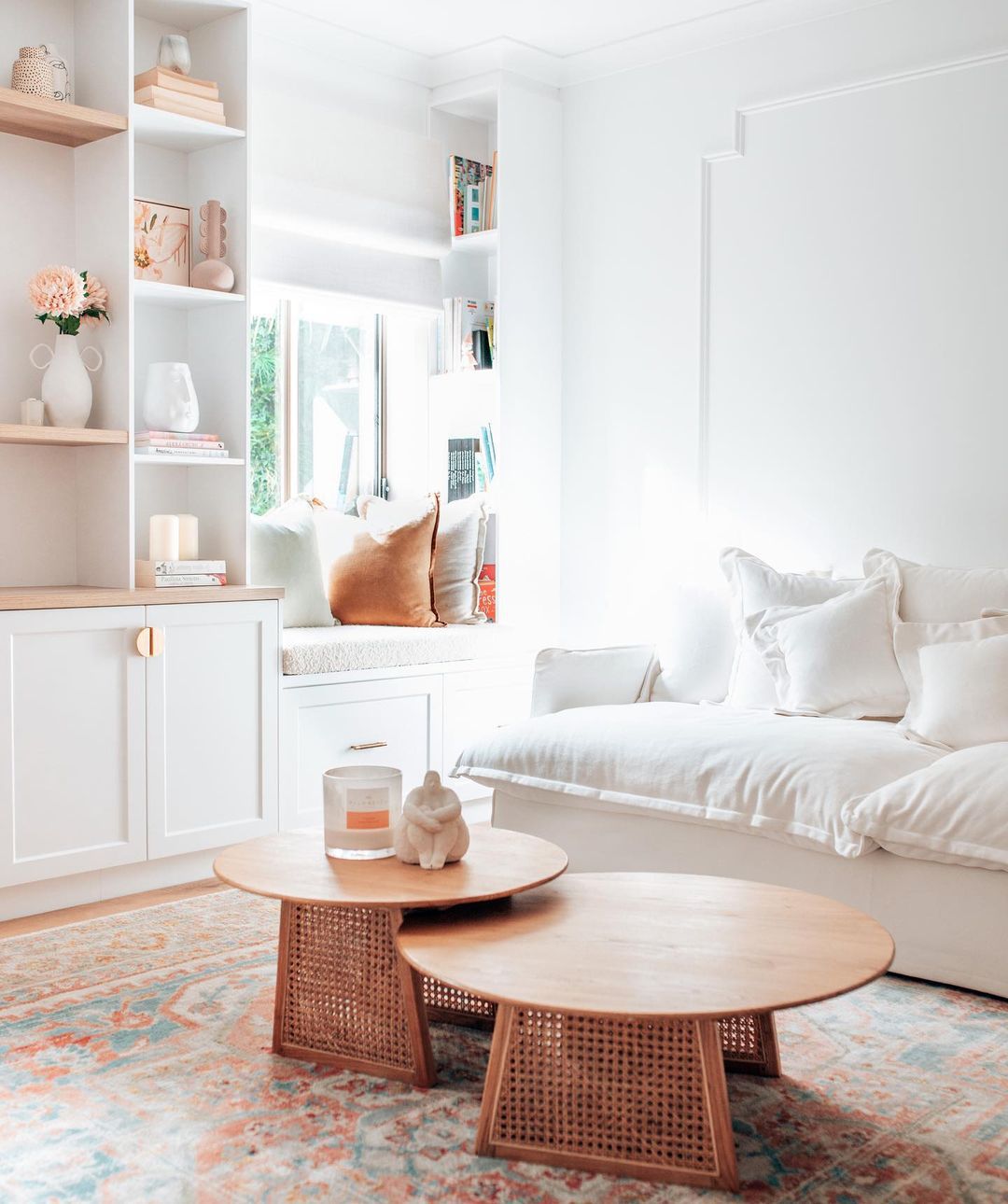 Un salon blanc avec des tables basses rondes en bois.