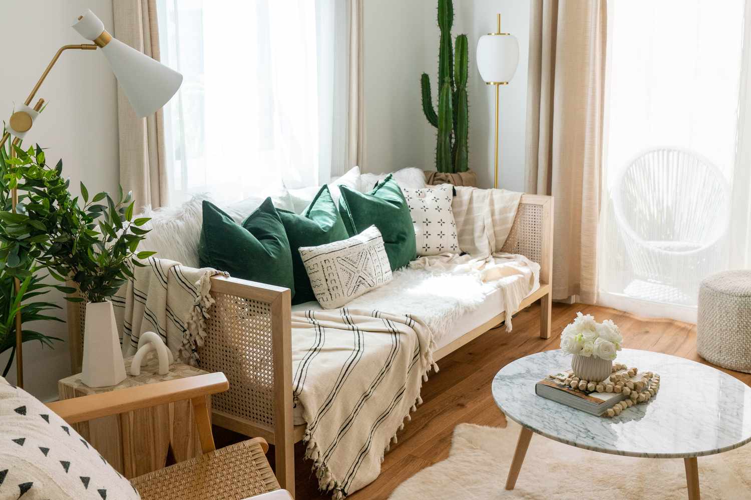 Canapé en bois avec couvertures et oreillers à motifs près d'une fenêtre lumineuse