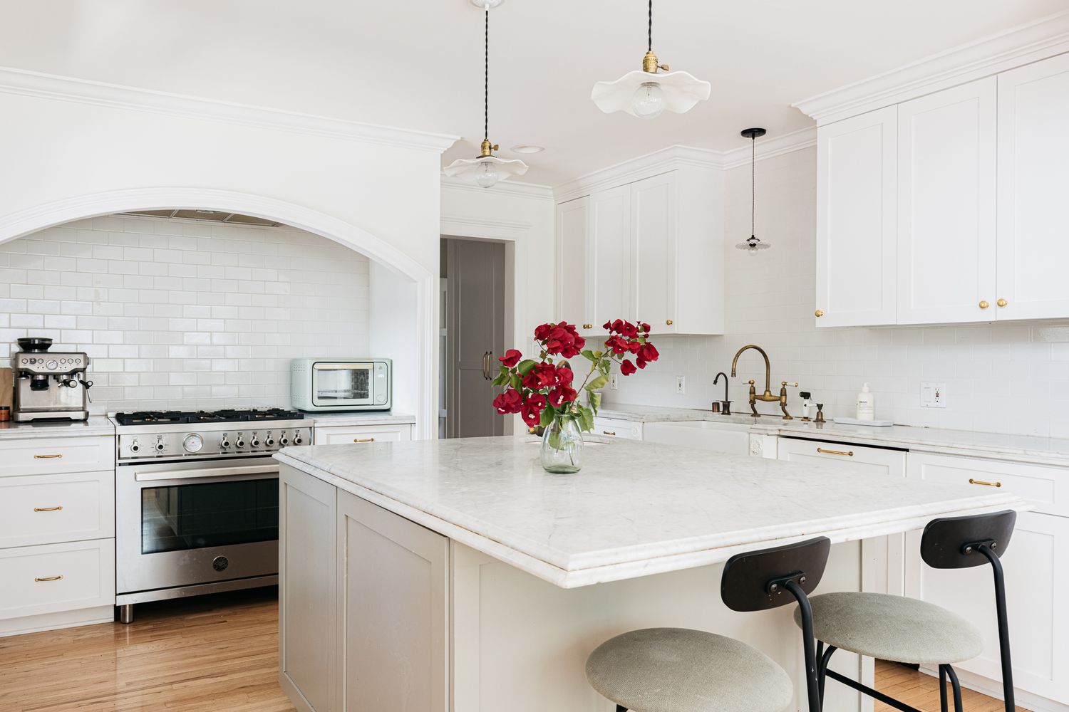 Weiße Küchenschränke in einer komplett weißen Küche mit roten Rosen in der Mitte