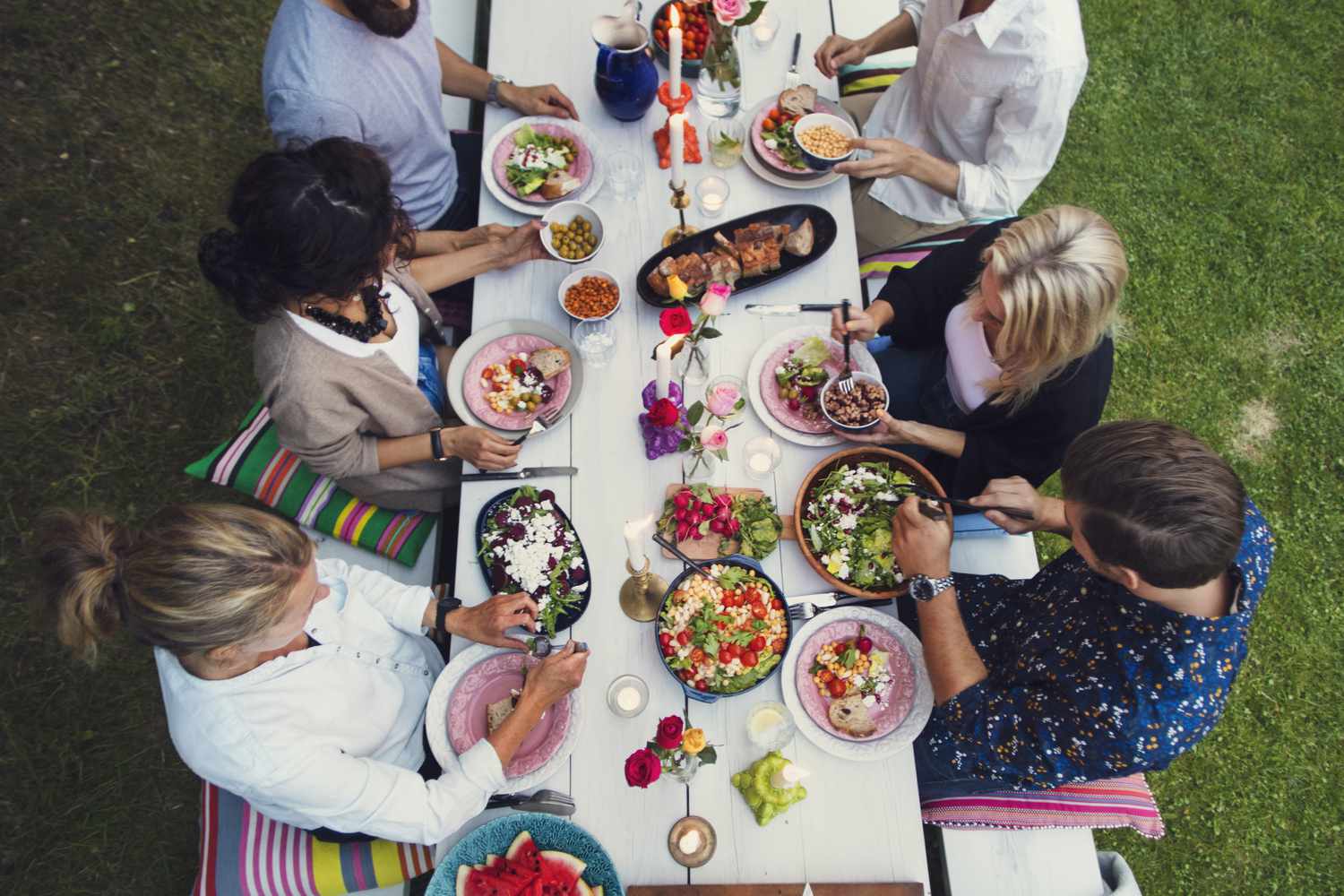 Amigos sentados en una larga mesa compartiendo una comida al aire libre