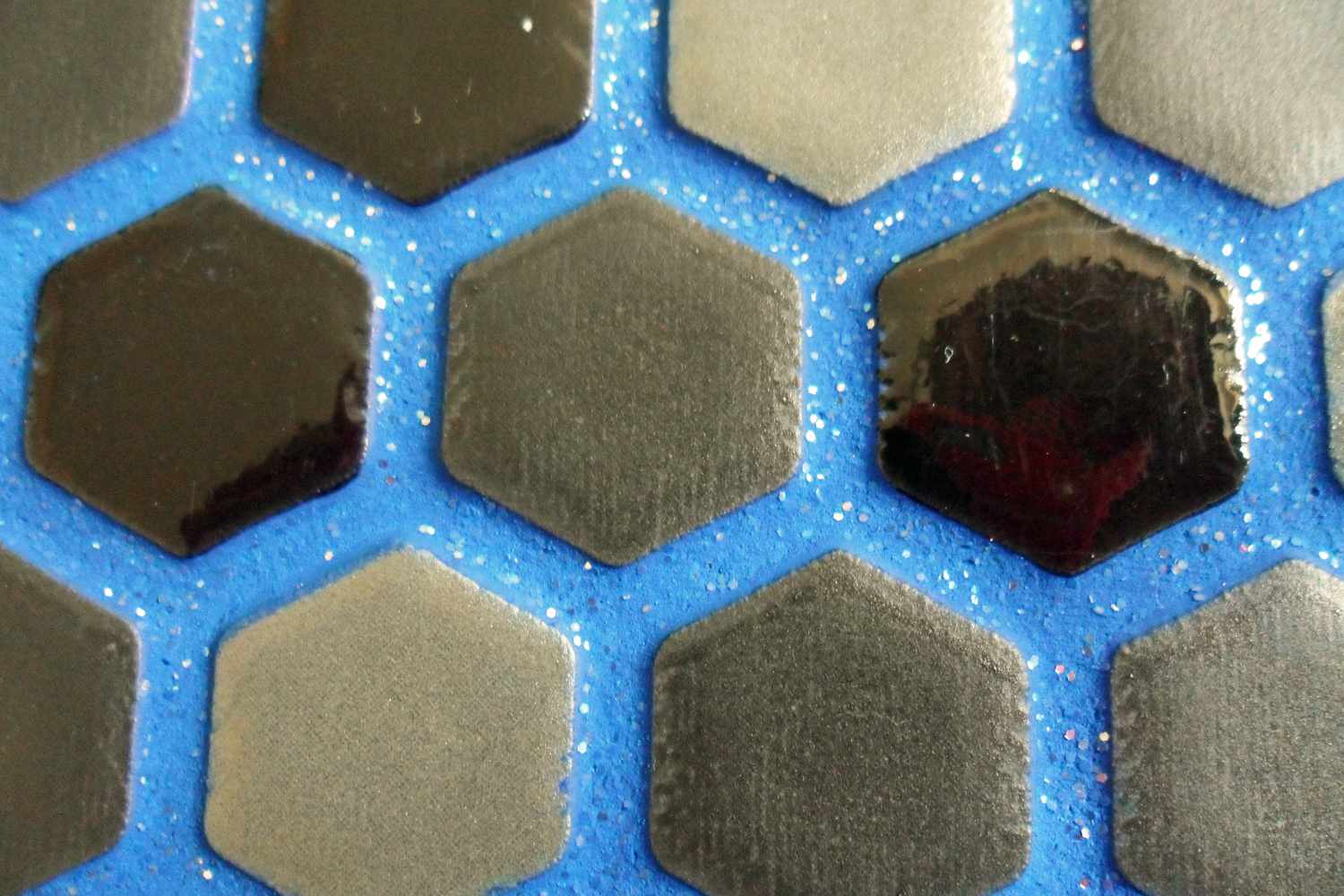 Azulejos hexagonais pretos com rejunte azul cintilante