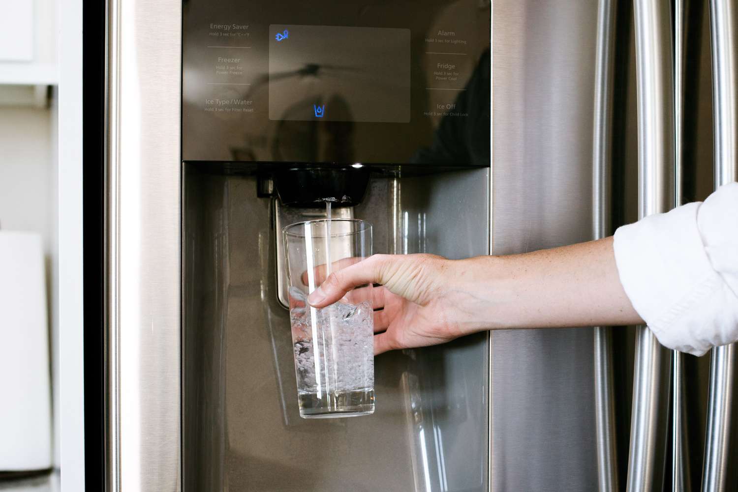 Vertiendo agua en un vaso desde el filtro de agua del frigorífico
