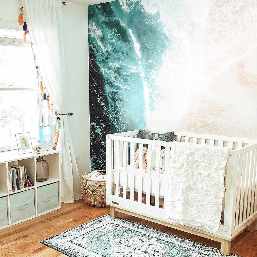 Chambre d'enfant d'inspiration bohème sur le thème de la plage avec une fresque graphique de l'océan