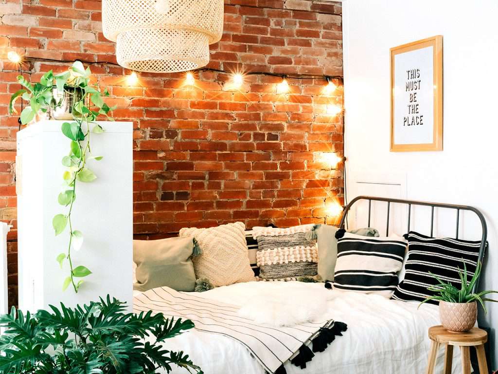 Zimmer mit einem Bett und Lichtern und einer Backsteinwand